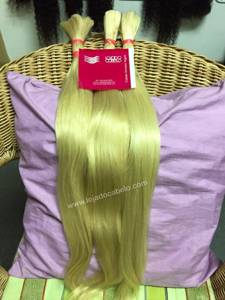 Três madeixas de cabelo louro solto, atadas no topo, expostas sobre uma cadeira.