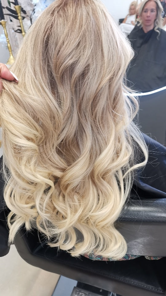 Loiro com balayage e extensões, finalizado com ondas largas.