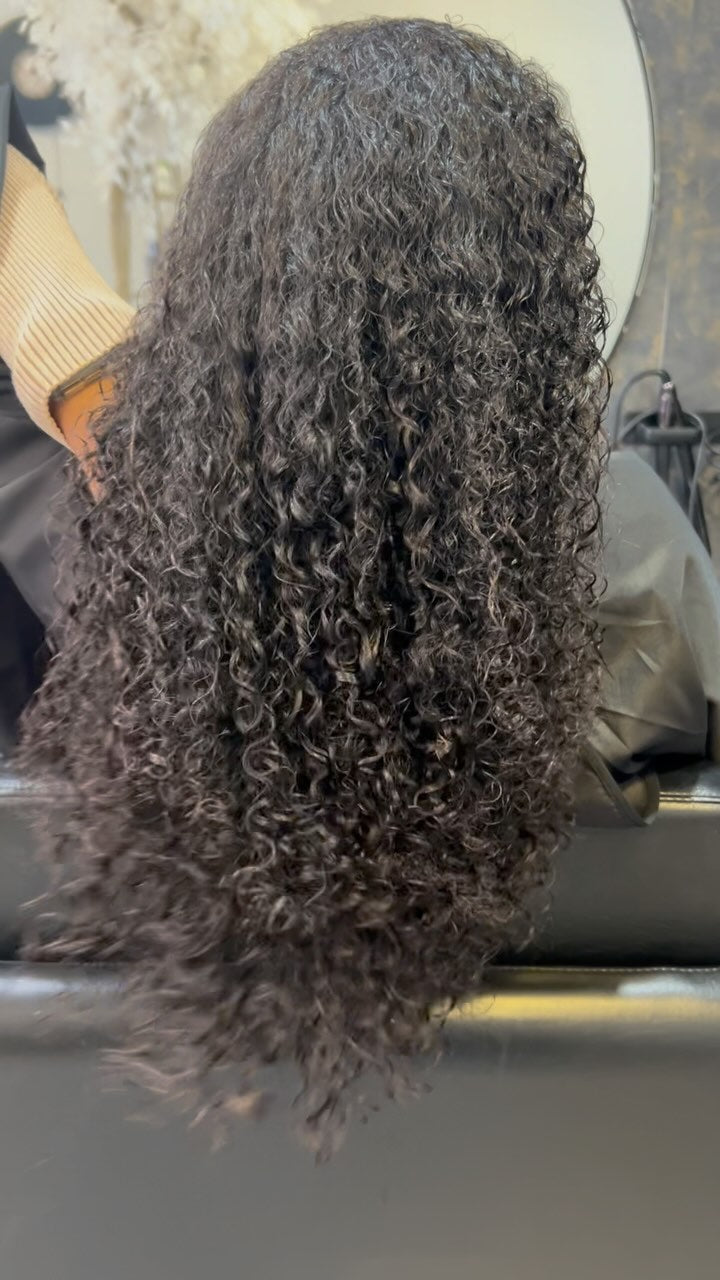Cabelo escuro cacheado visto de costas, numa aplicação da Loja do Cabelo.