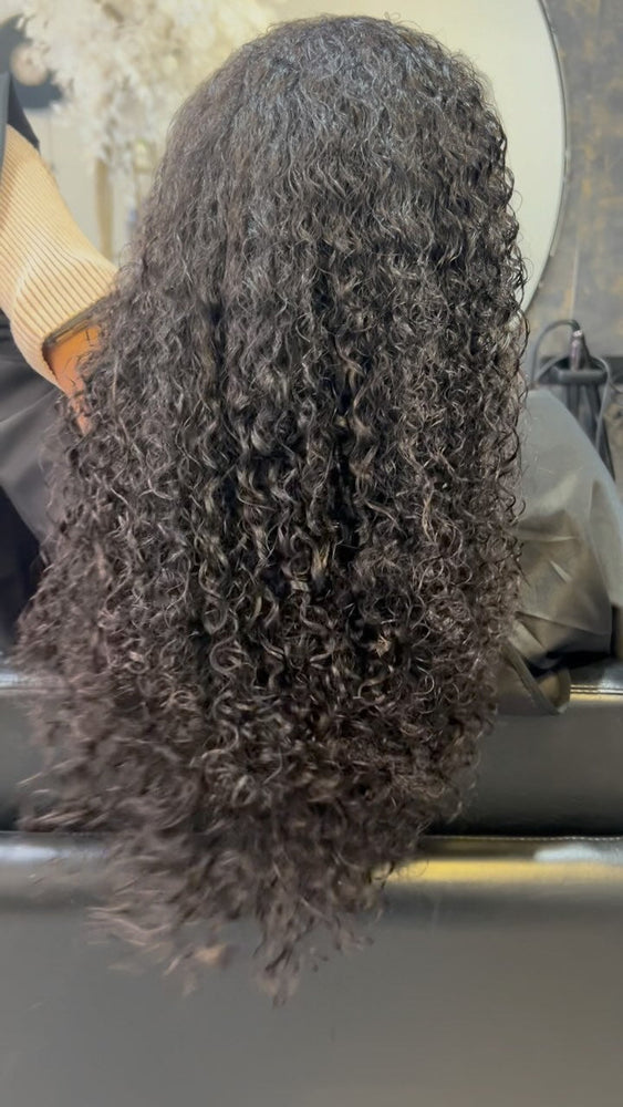 Cabelo escuro cacheado visto de costas, numa aplicação da Loja do Cabelo.
