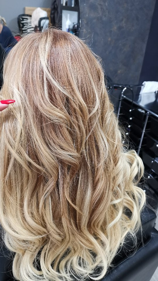 Cabelo loiro com reflexos e ondas, após aplicação de extensões e correção de cor.