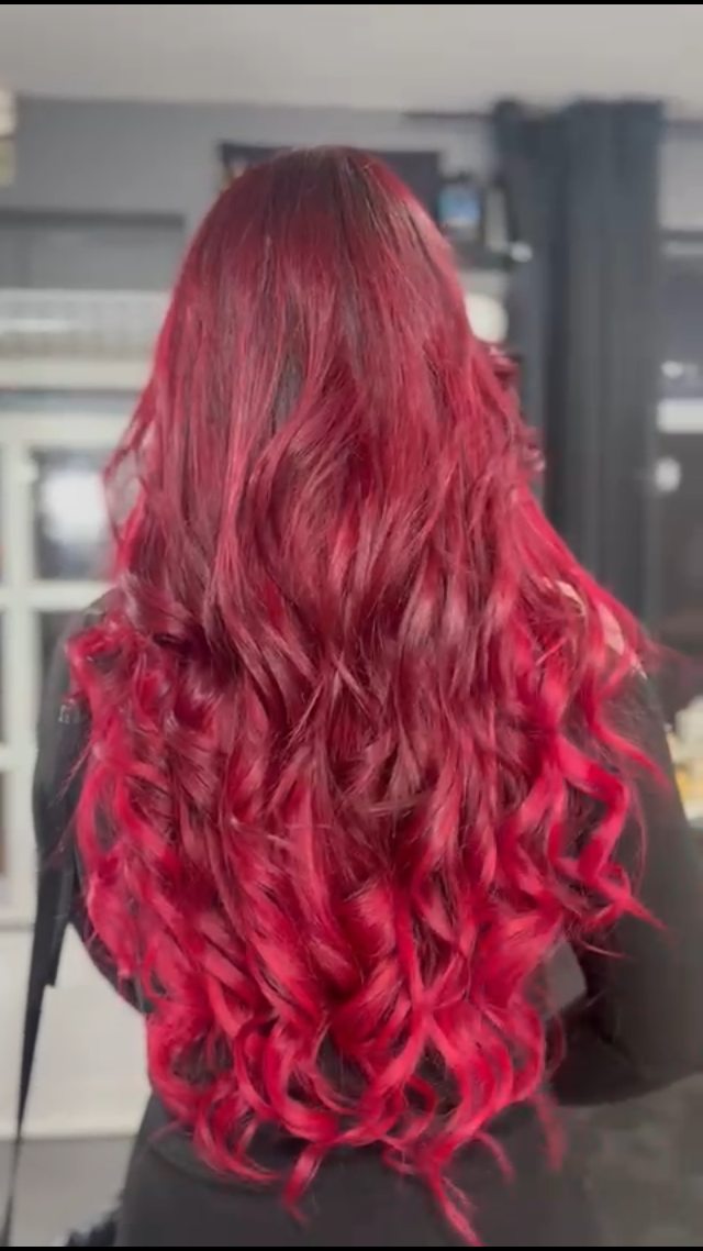Cabelo vermelho intenso com acabamento ondulado, num trabalho da Loja do Cabelo.